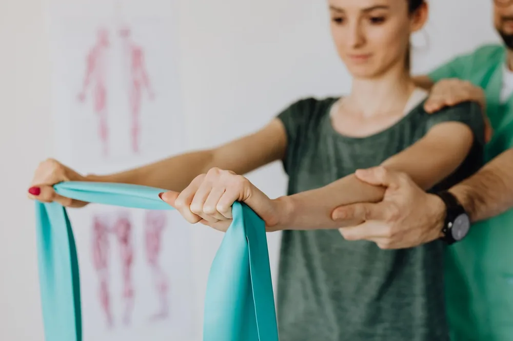 A clinician working a shoulder with a resistance band