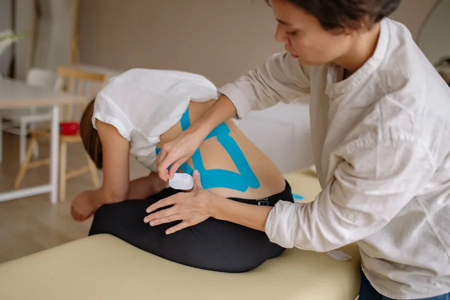Kinesiology tape being applied to a lower back