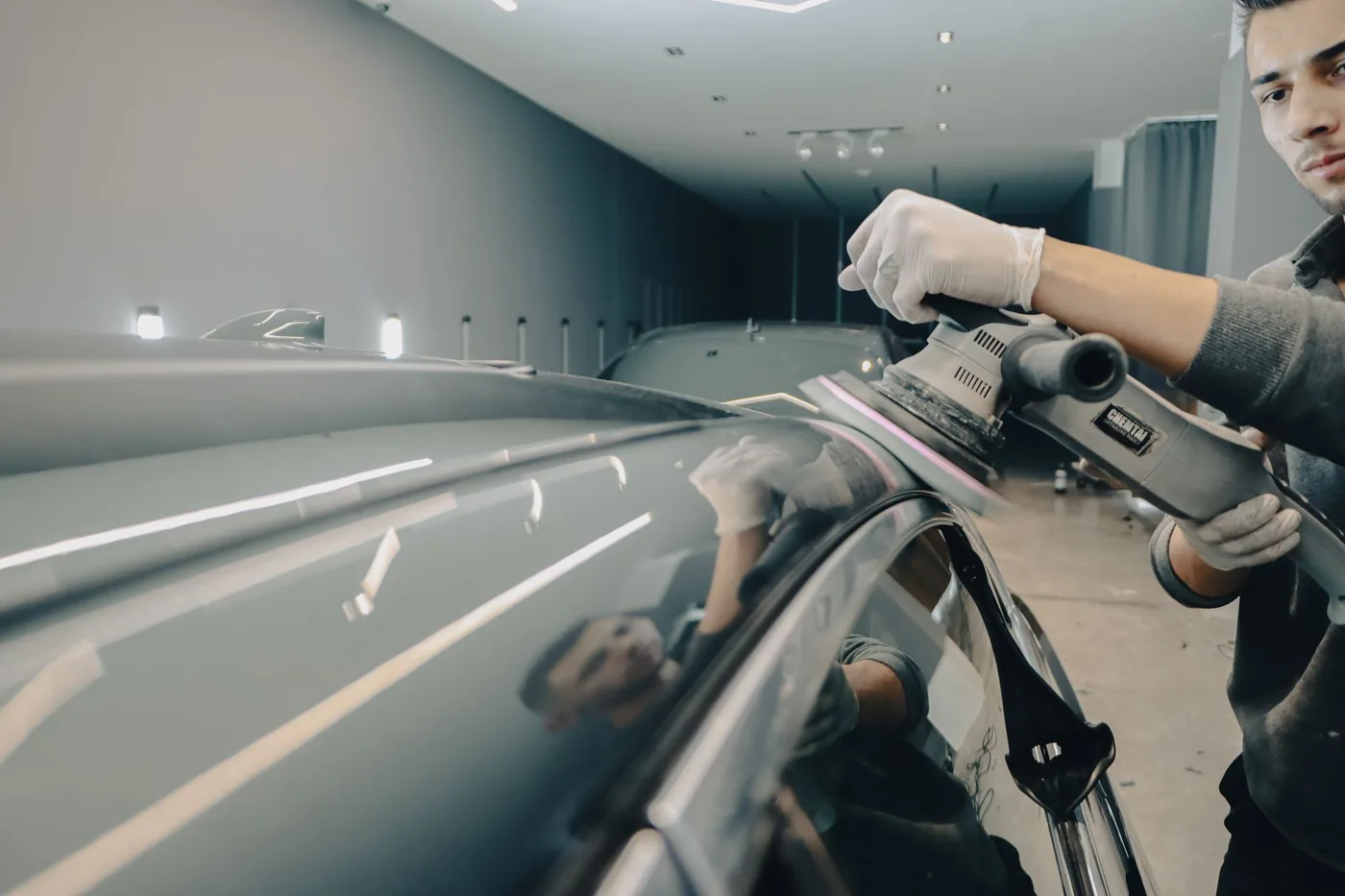 A machine polisher being worked across a bonnet