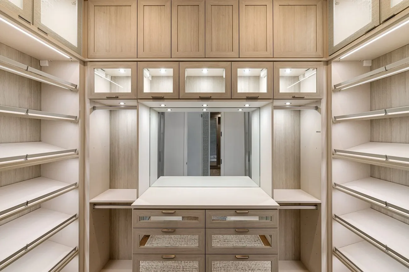 A walk in dressing room with lit oak shelving and drawers