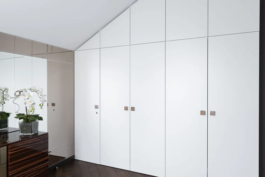 White fitted wardrobes under a sloping loft ceiling