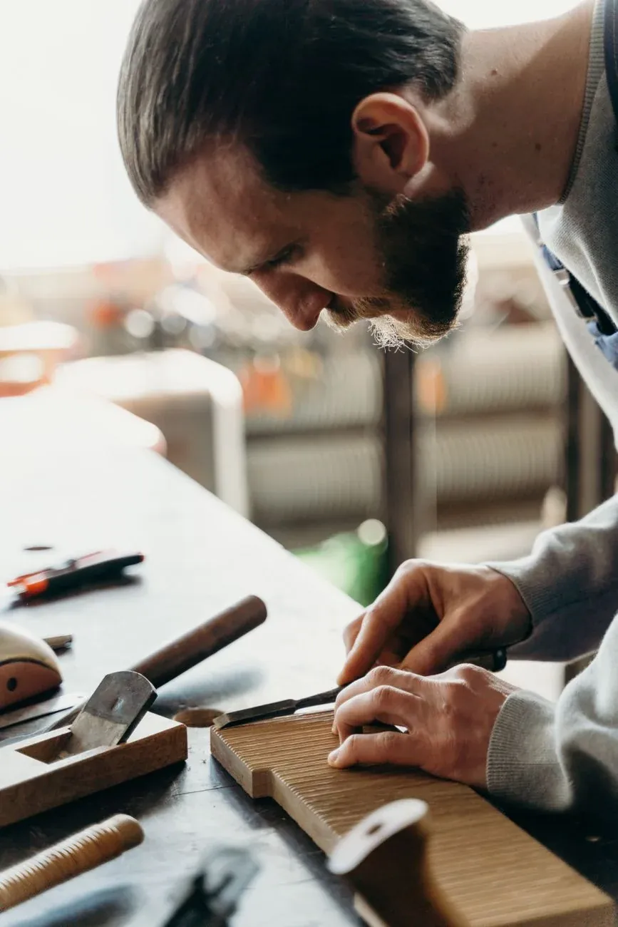A joiner marking a board with a pencil and a square
