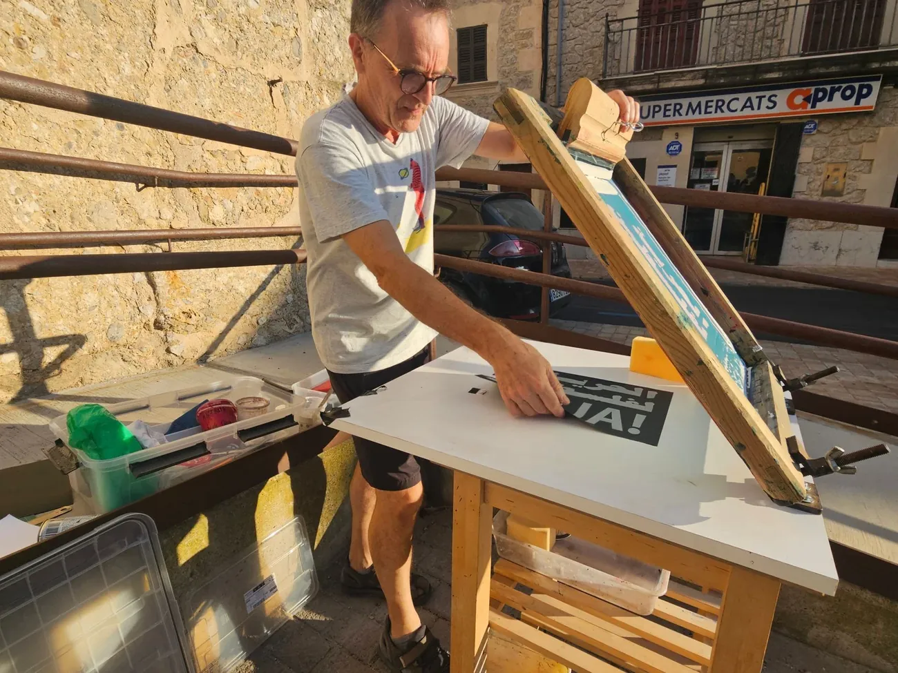 A sign maker cutting a panel on a bench in a busy workshop
