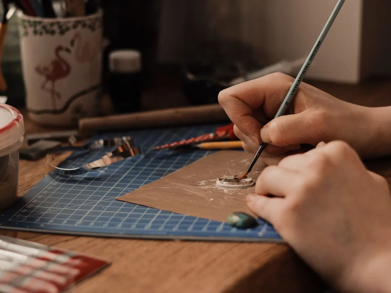 A signwriter painting a letter with a fine brush at a workbench