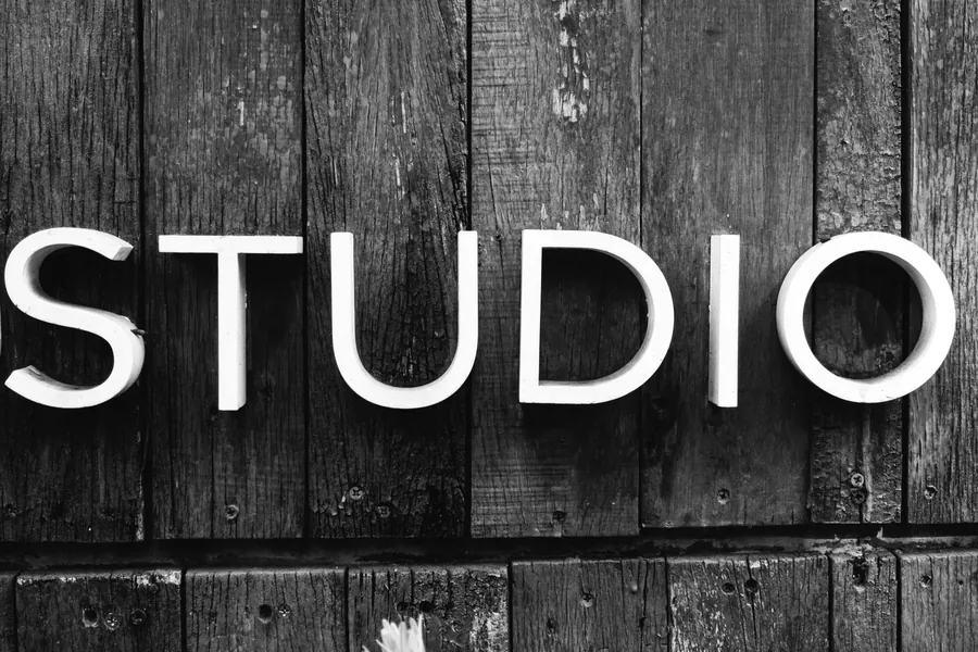 Built up white letters spelling Studio mounted on dark timber boarding