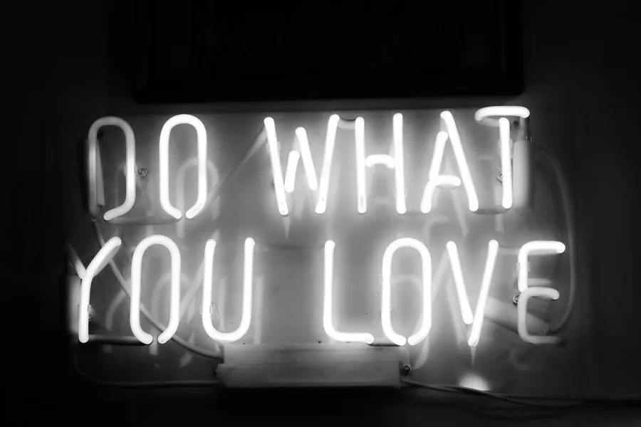 A white neon sign reading do what you love on a plain wall