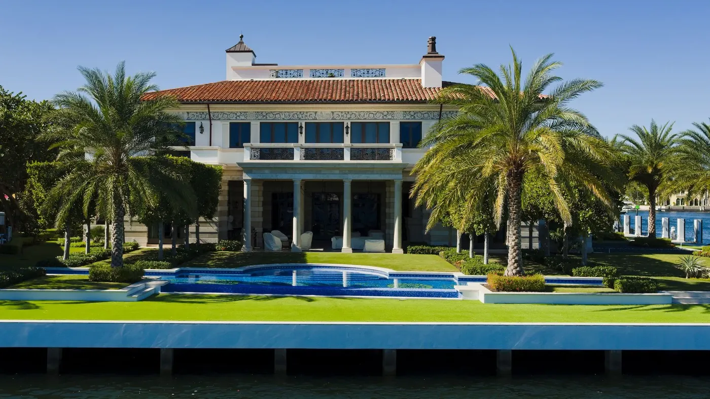 A Mediterranean style waterfront house with palms and a long pool
