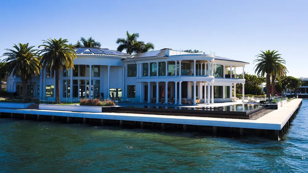 A modern white house with an infinity pool on the water