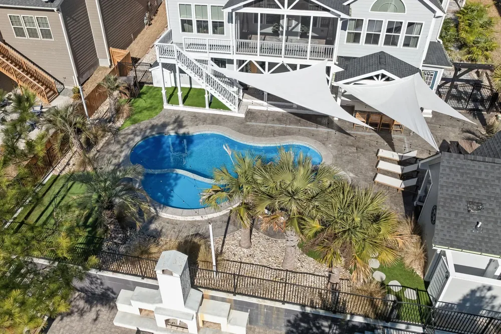 An aerial view of a freeform pool and spa in a back yard