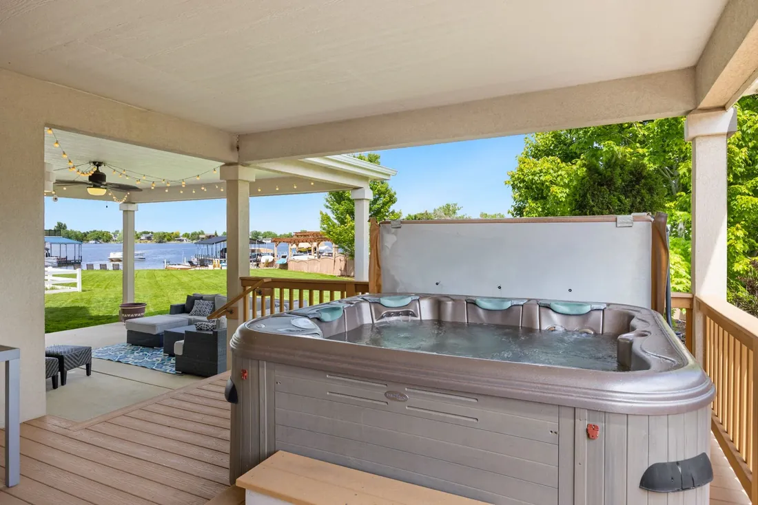 A hot tub under a covered porch looking out over a lawn