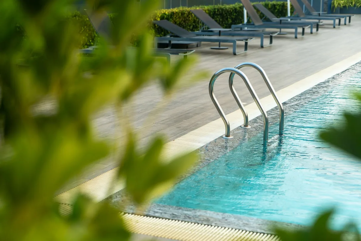 A pool ladder and coping on a bright day