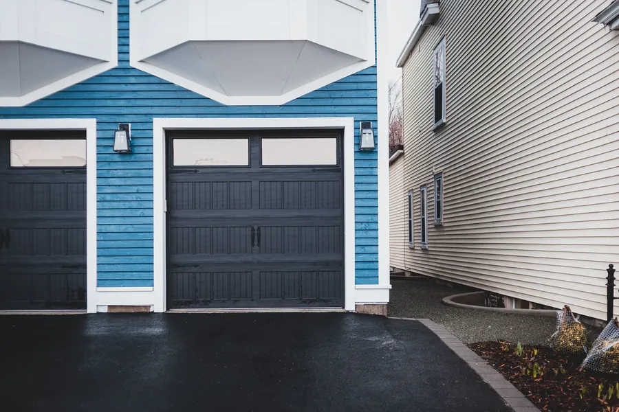 Black carriage style garage doors on a blue house