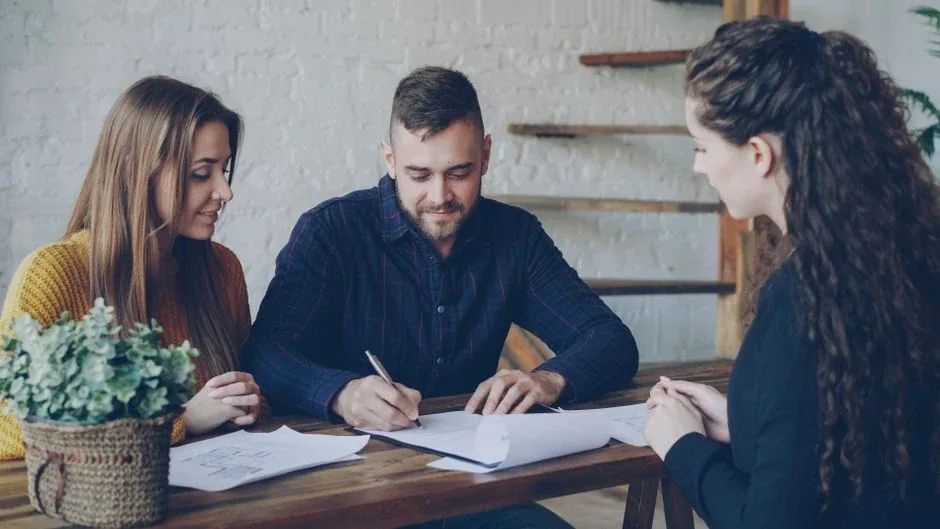 A couple signing at their kitchen table with the notary