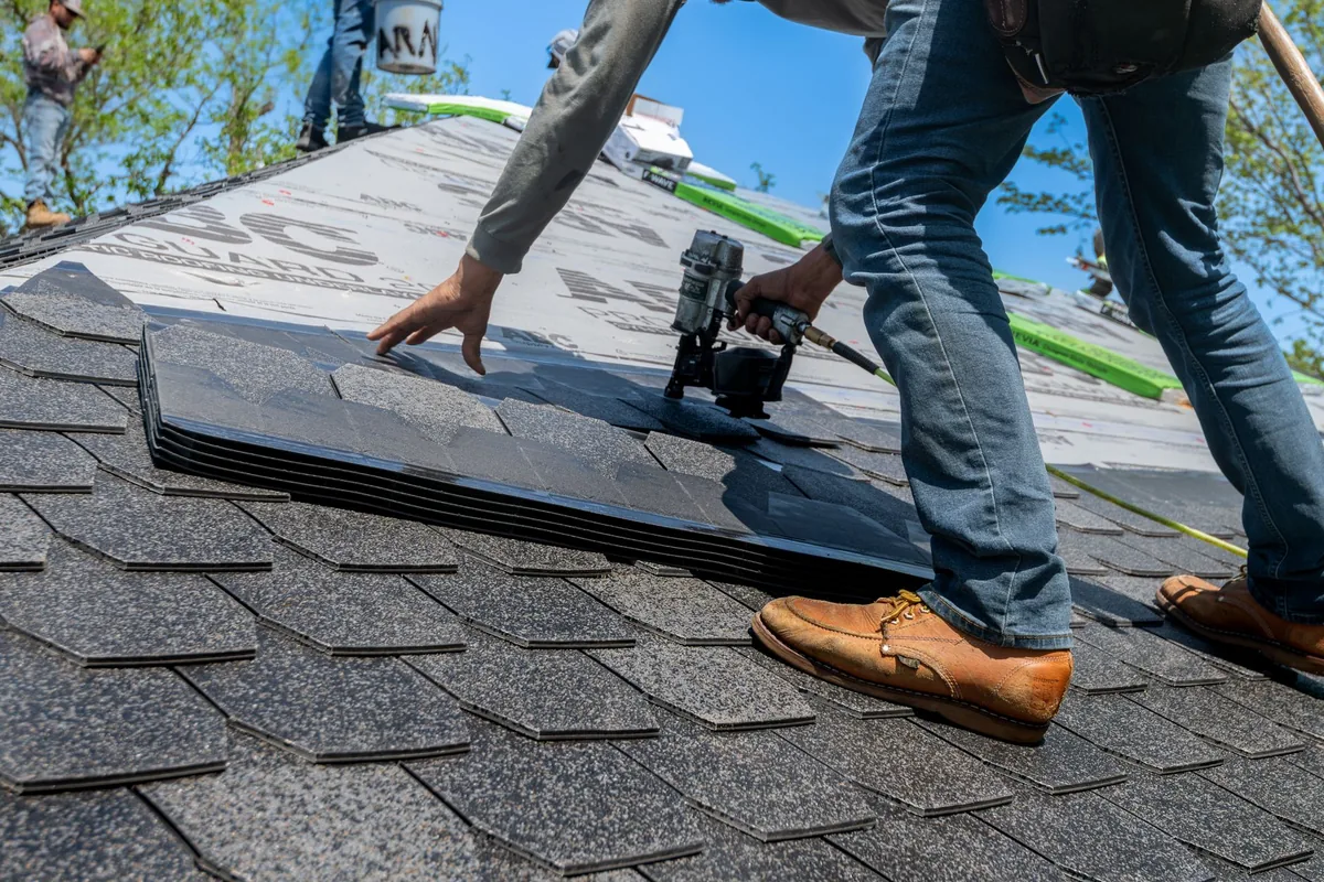 A roofer fixing new roof covering in place