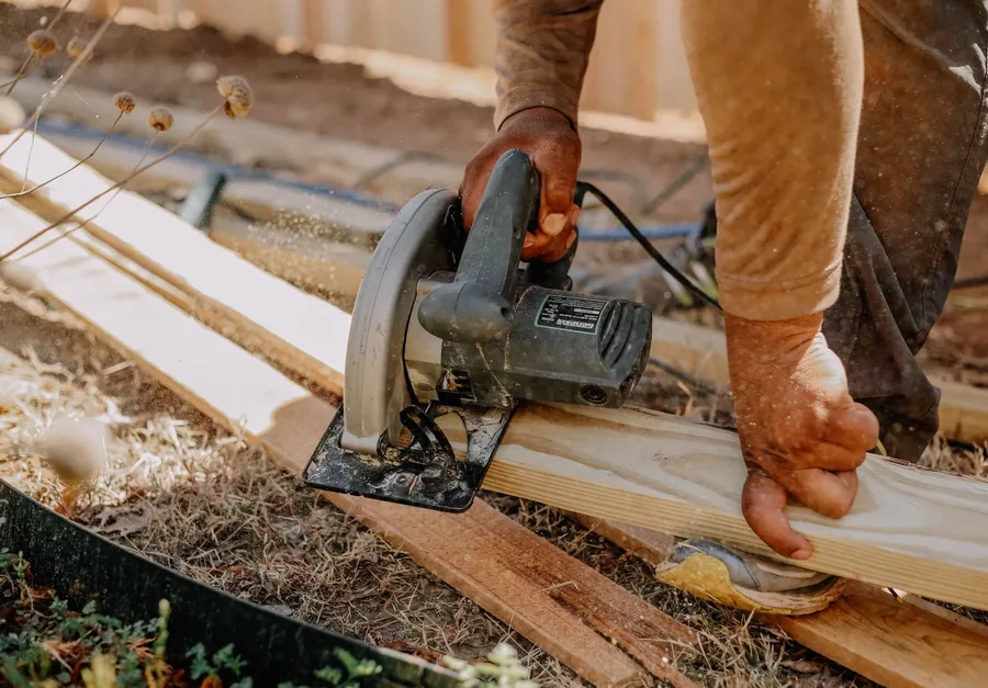 A carpenter cutting a deck board with a circular saw