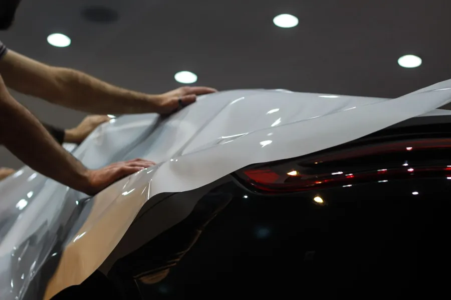 Clear protection film being fitted over the rear of a dark car