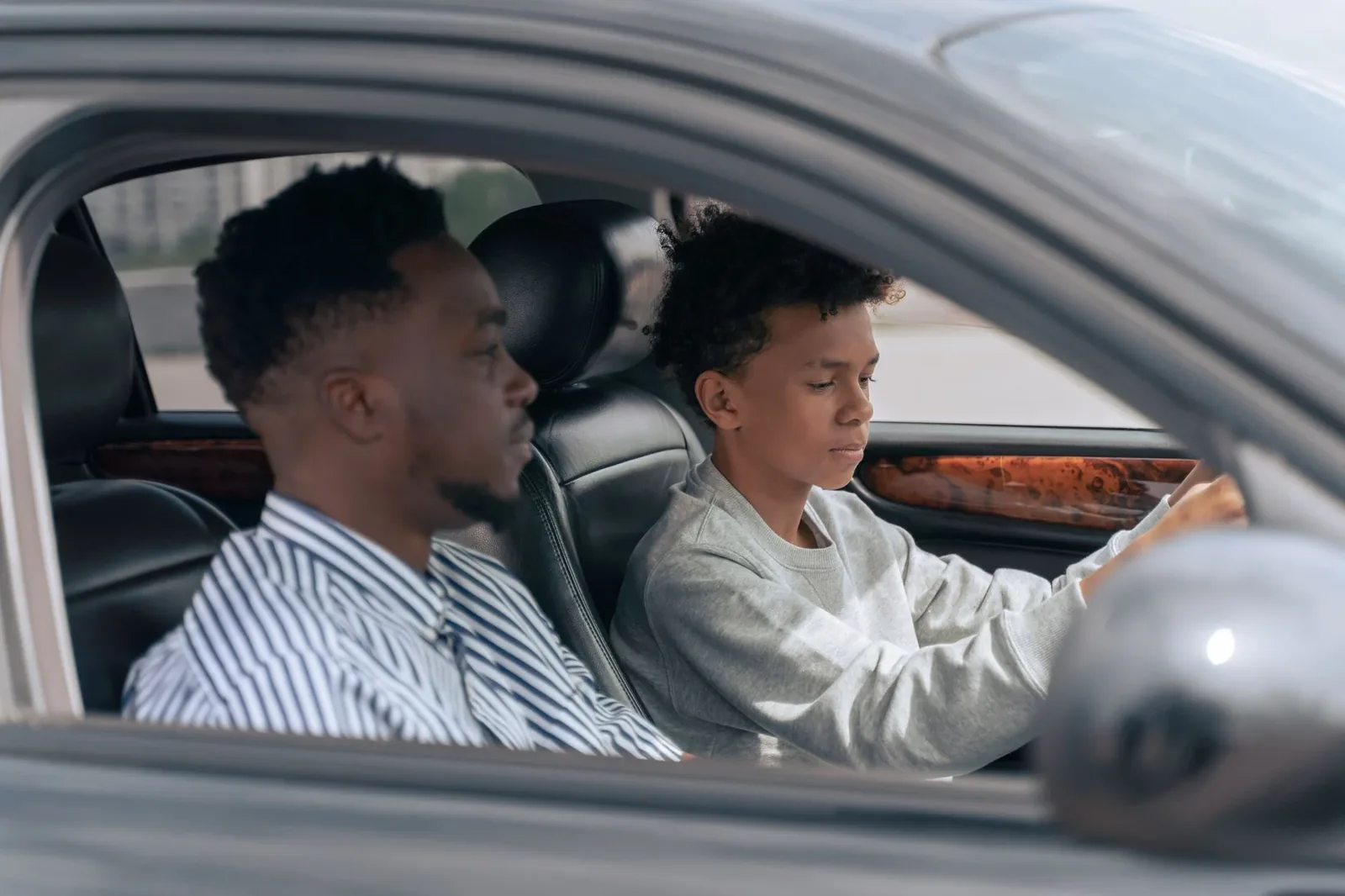 A driving instructor beside a teen learner at the wheel