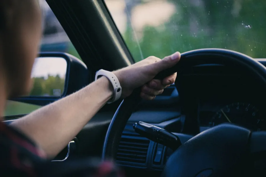 A learner's hands on the wheel in traffic