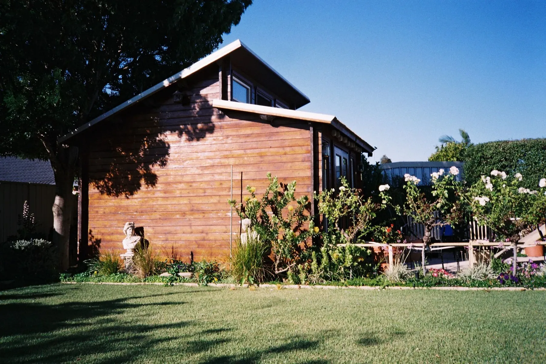A cedar clad garden room on a sunny lawn