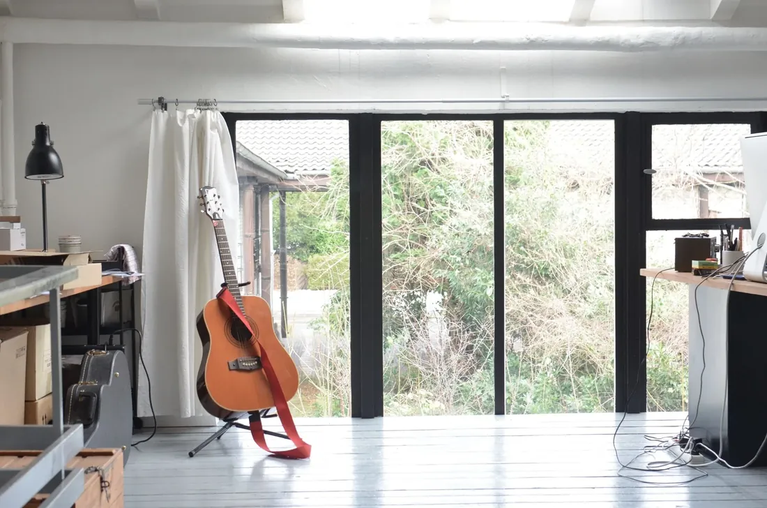 A bright garden studio with a guitar and glass doors onto the garden