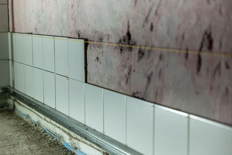 Water stains across a tiled bathroom wall