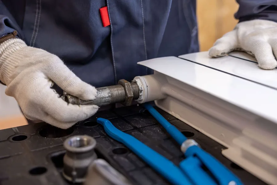 Gloved hands repairing a leaking pipe joint