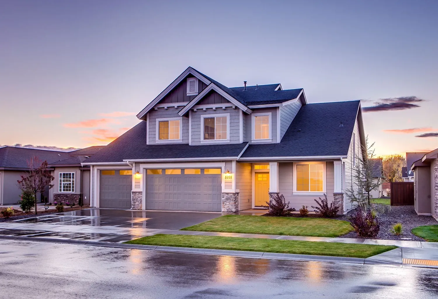 A two story house at dusk with its lights on
