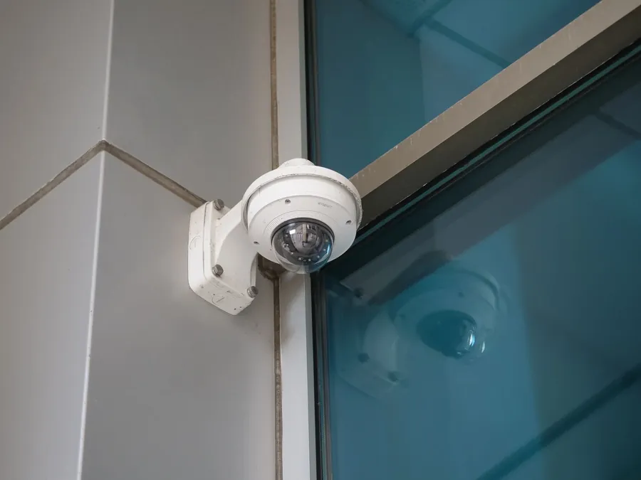 A white dome camera mounted on an outside wall