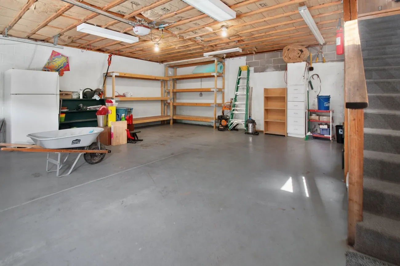 A bare concrete garage floor with shelves and tools, before coating