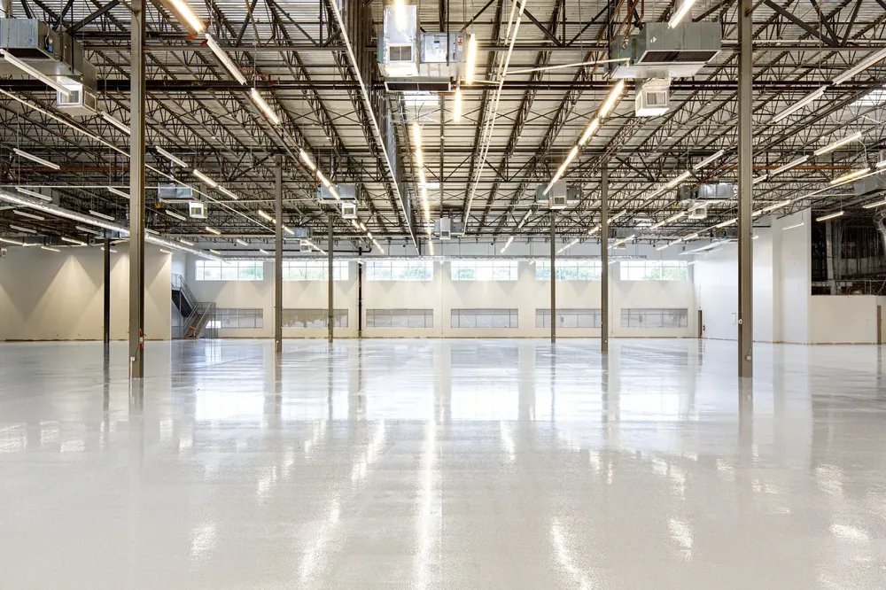 A long glossy white warehouse floor under rows of lights