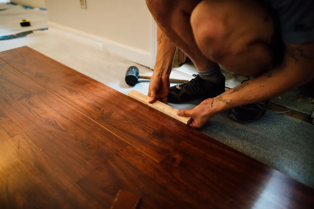 An installer tapping a dark hardwood board into place