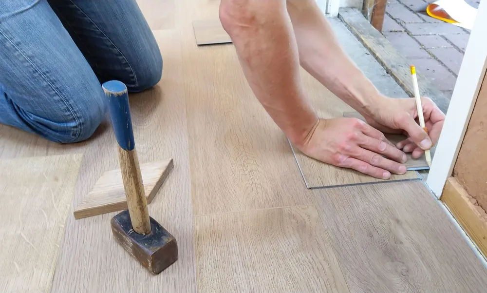 An installer measuring and marking a vinyl plank