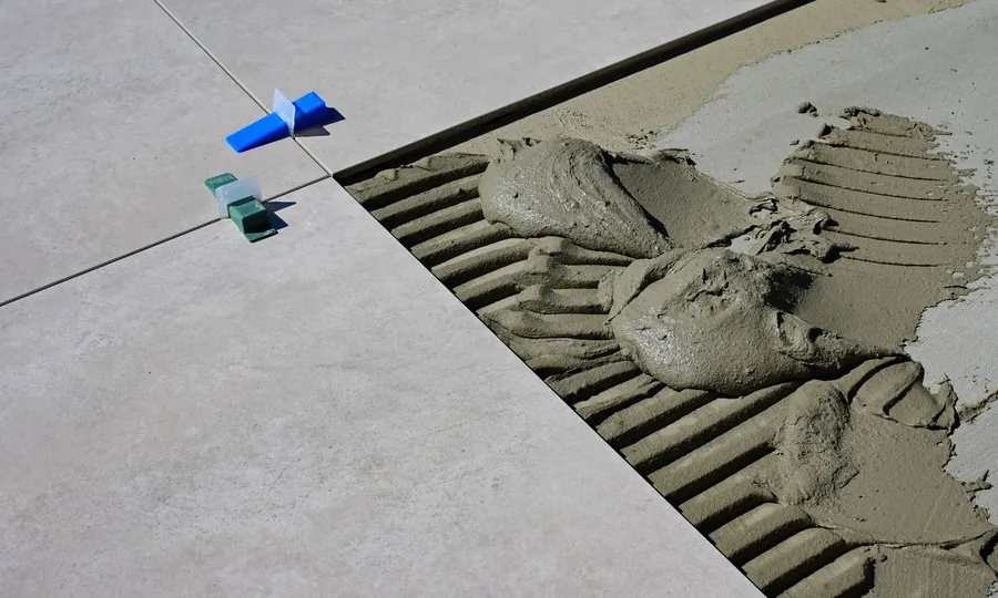 Adhesive being spread with a notched trowel before tiling