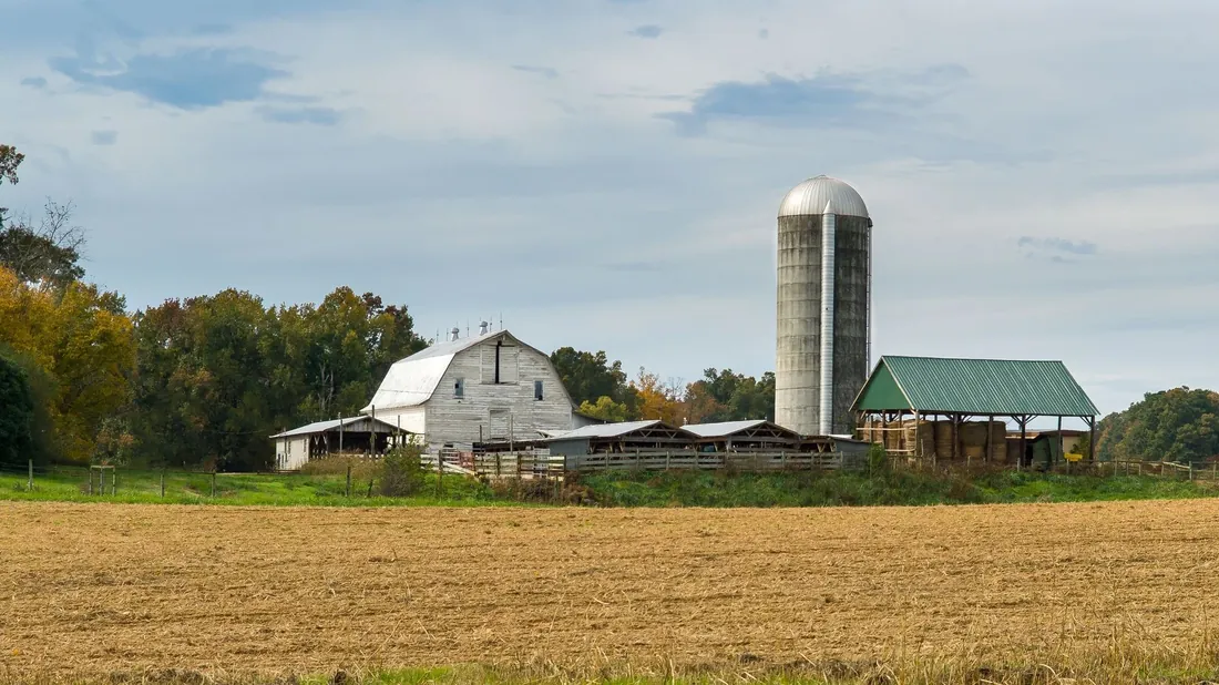 A white barn and silo beside a field in the East Tennessee countryside