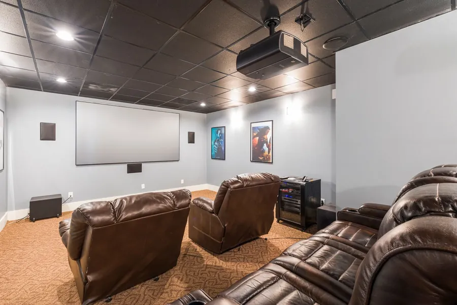 A dedicated cinema room with leather recliners, a ceiling projector and a large screen