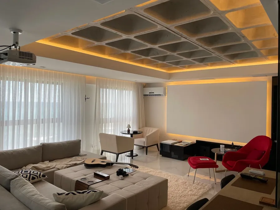 A living room with a white projector screen, sofas and a coffered ceiling