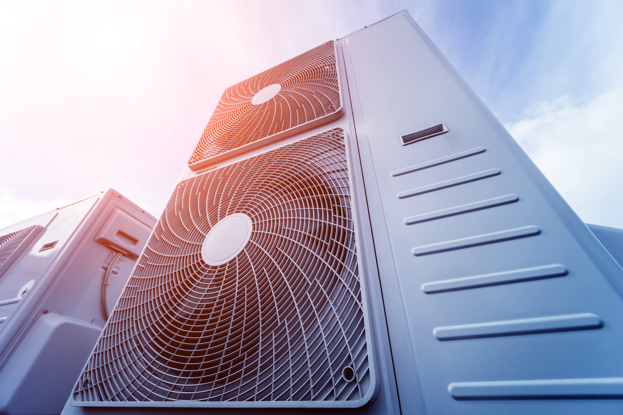 Rooftop air conditioning condensers against a bright sky