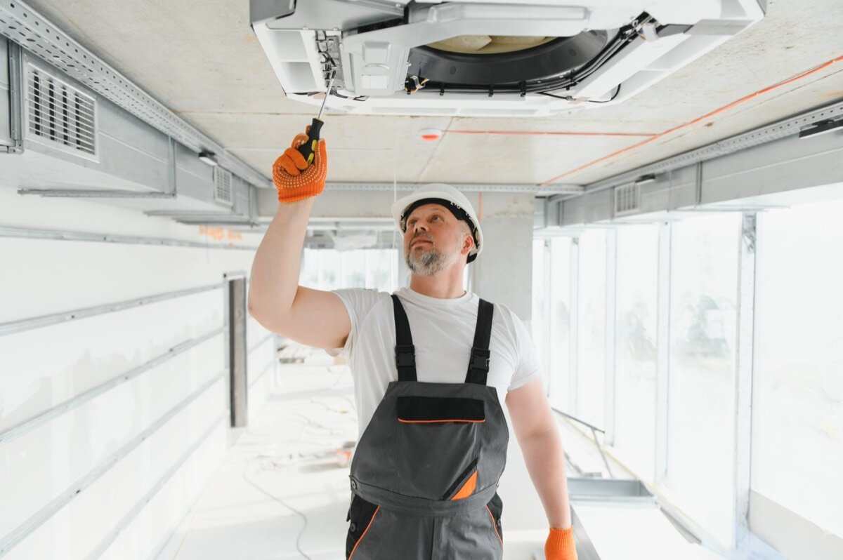 Technician installing a ceiling air conditioning unit