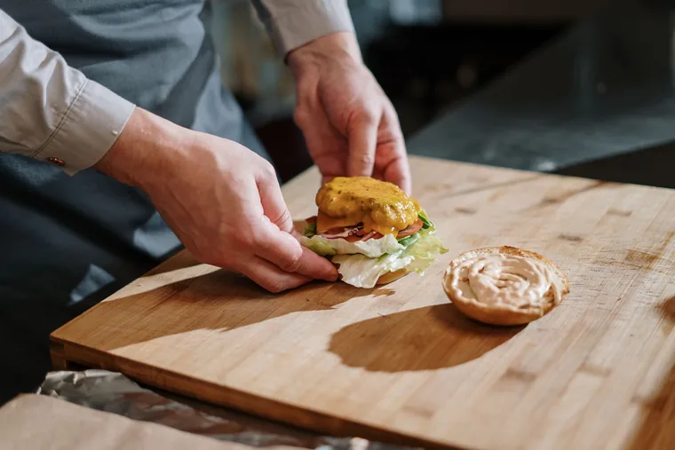 A smash burger being built on a board