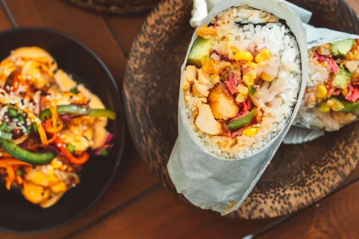A burrito cut open beside a bowl of rice