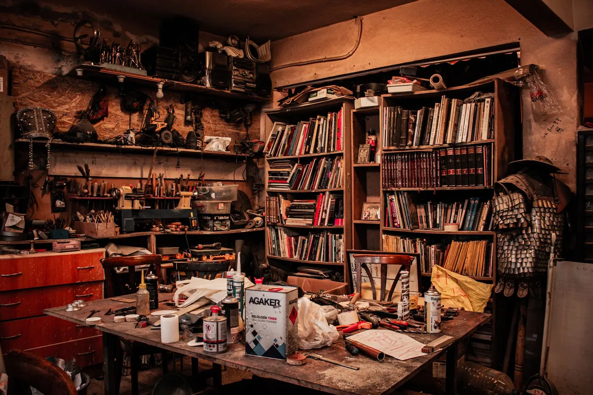 A crammed room full of furniture, books and clutter