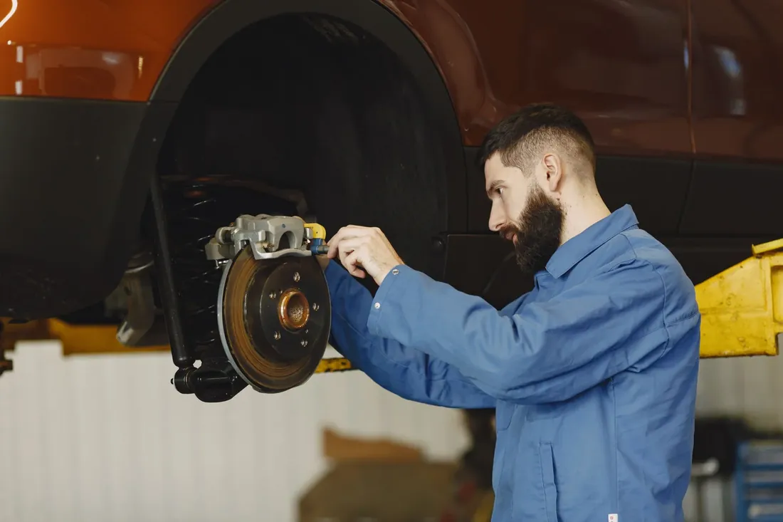 A mechanic fitting a brake caliper over a new disc