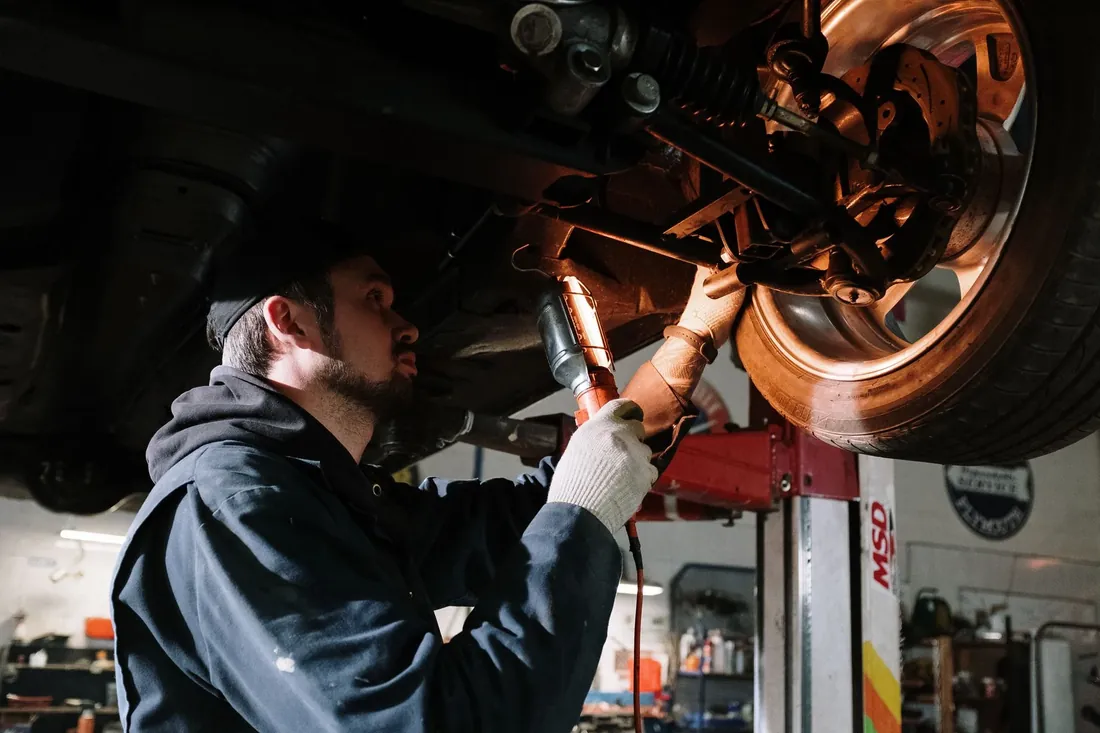 A mechanic checking the underside of a car with a torch