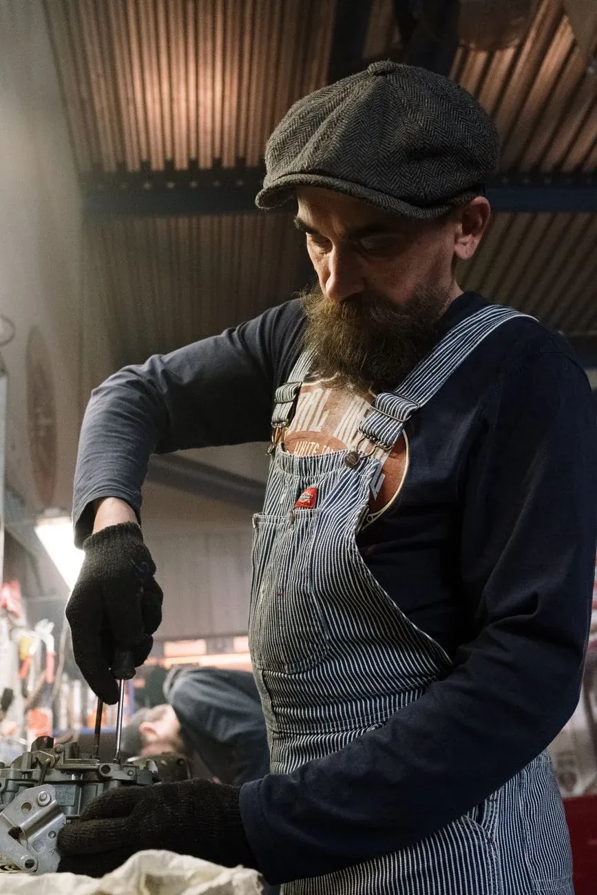 Rob Hale in overalls and a flat cap at the workbench