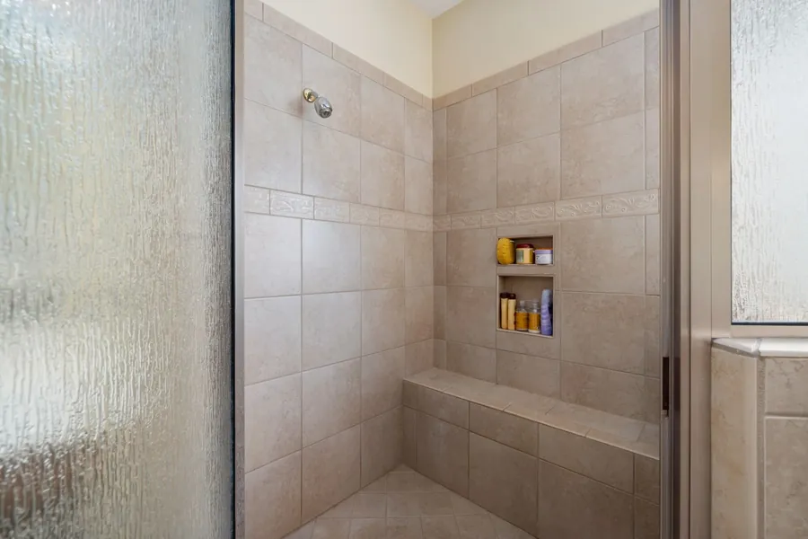A tiled shower with a built in bench seat and a recessed shelf