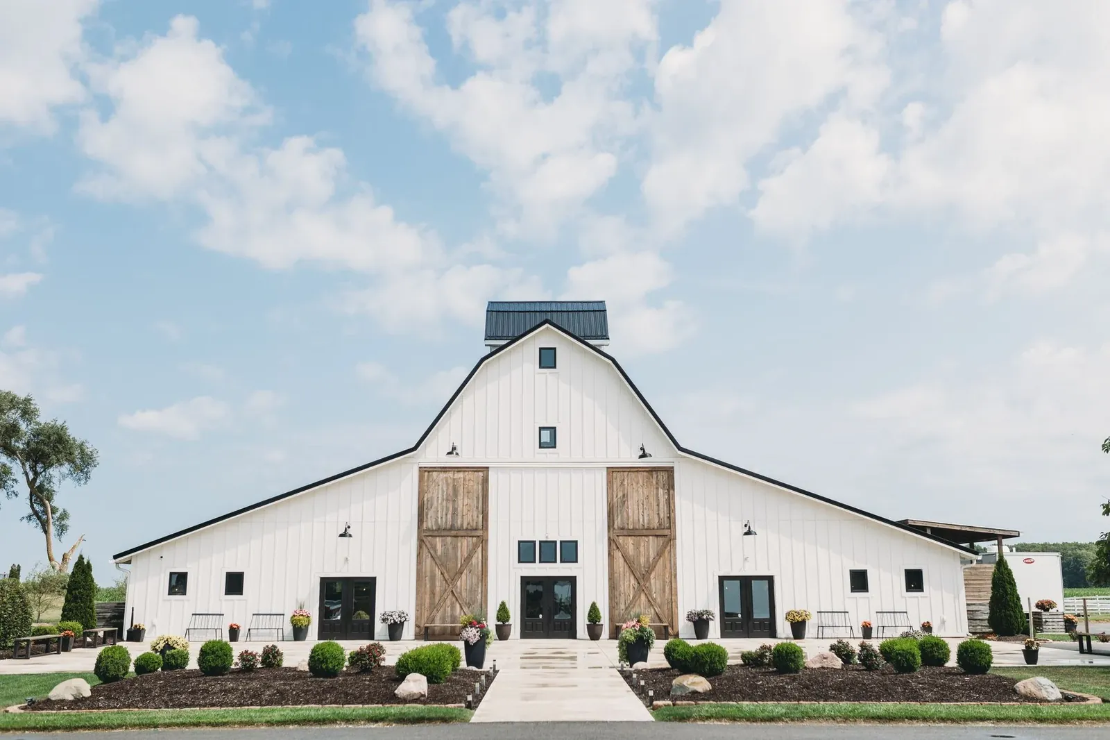 A white barn with tall wooden sliding doors under a blue sky