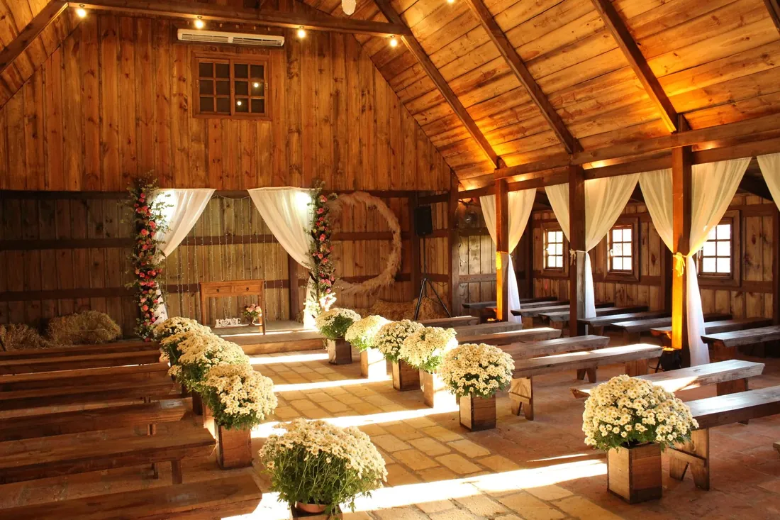 Wooden pews and white flowers in a timber chapel barn lit by warm sunlight