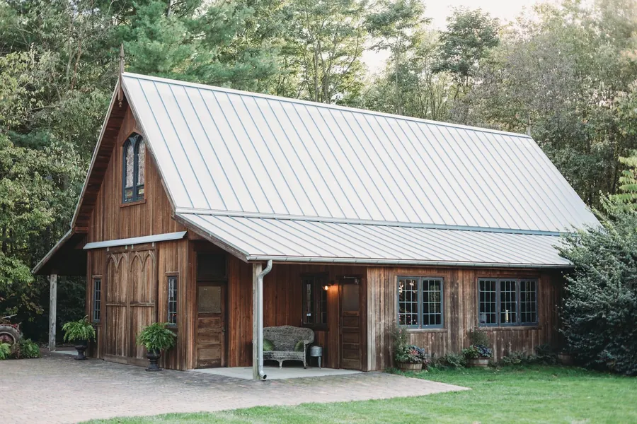 A timber cottage with a metal roof on a green lawn