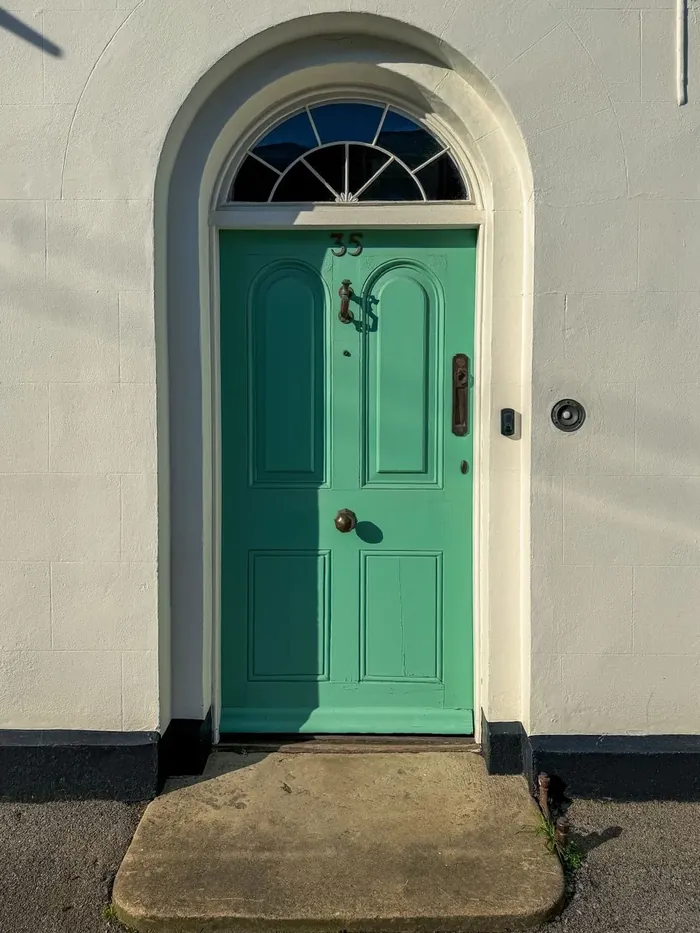 A green arched front door with a fanlight