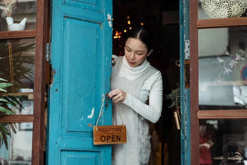 A shop owner turning the sign on a blue door to open